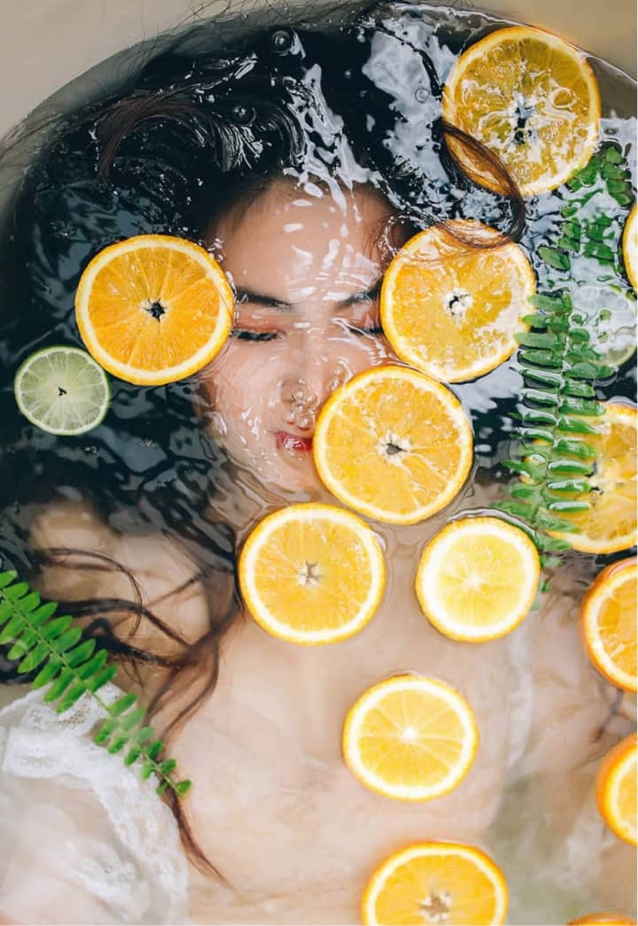 تصویری ازماساژ درمانی آرامش بخش در تهران، با استفاده از برش های پرتقال و برگ های سبز در آب، مناسب برای افزایش سلامت و طراوت پوست و بدن.